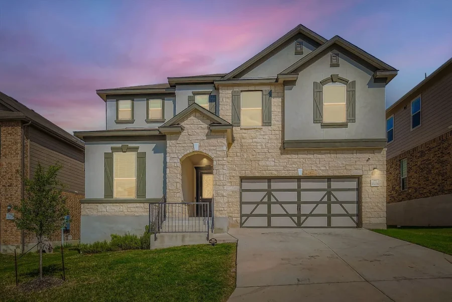 Two-story house exterior with garage, front steps and lawn