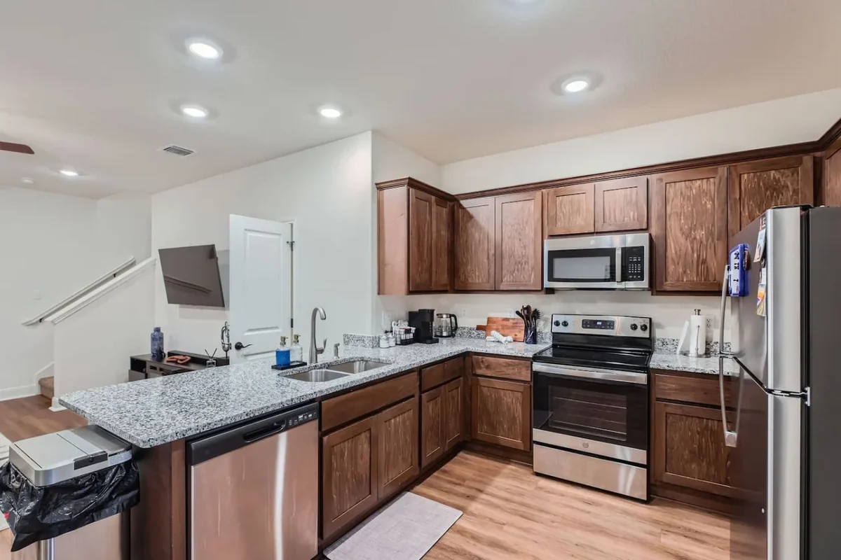 Duplex kitchen with dark wood cabinets, stainless steel appliances and a peninsula counter